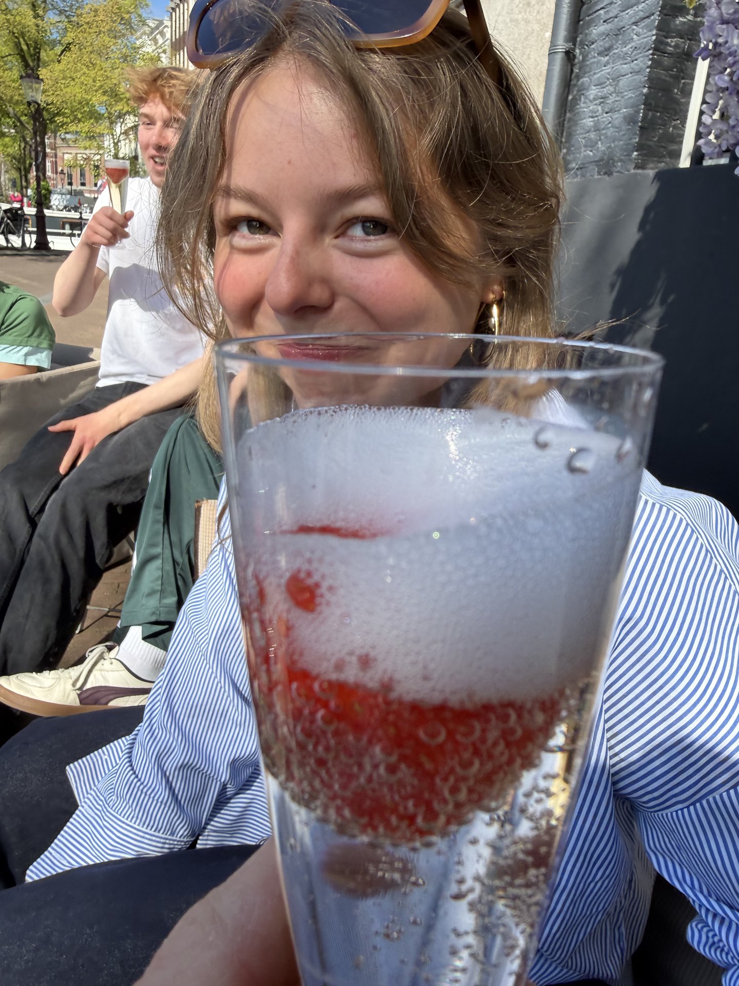 This vibrant photo captures a cheerful moment at Staalkade, Centrum, Amsterdam, with friends enjoying sparkling drinks outdoors